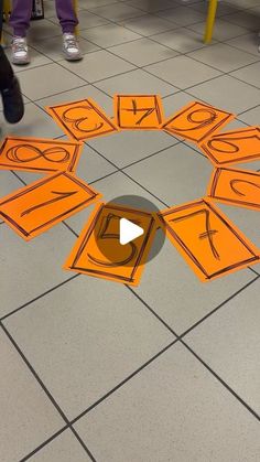 a group of people standing around an orange circle with numbers cut out on the floor