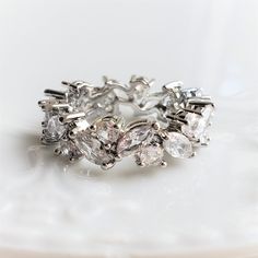 a close up of a ring on a white plate with water droplets and diamonds in it