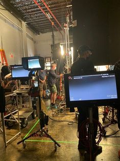 a group of people standing around in a room with monitors on the floor and lights behind them