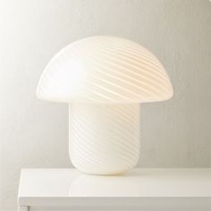 a white mushroom lamp sitting on top of a table next to a wall mounted clock