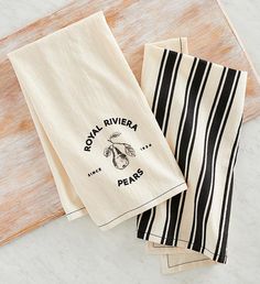 three tea towels sitting on top of a wooden cutting board next to each other with the words royal riviera and pears printed on them