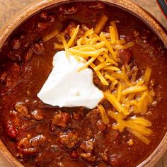 chili with cheese and sour cream in a brown bowl on a wooden table, ready to be eaten