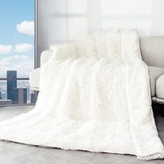 a white blanket sitting on top of a couch next to a window