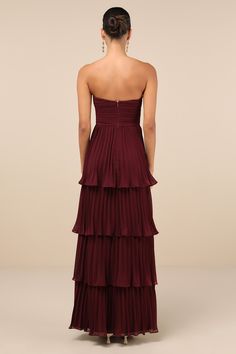 the back of a woman wearing a long dress with tiered layers and a high low neckline