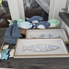 three wooden fish sitting on top of a table next to an open box filled with paper