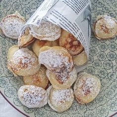 powdered sugar covered pastries on a blue and white plate next to a newspaper