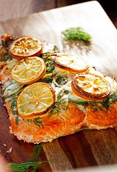 a piece of fish with lemons and herbs on it sitting on a cutting board