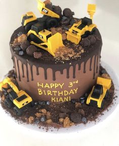 a birthday cake with chocolate frosting and construction trucks