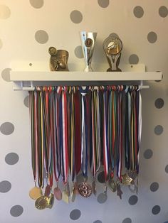 a wall shelf with medals and spoons hanging from it's sides on a polka dot wall