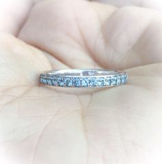 a woman's hand holding a wedding ring with blue stones