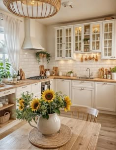 a kitchen with sunflowers in a vase on the table and white cupboards