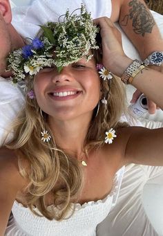 a man and woman laying next to each other with flowers in their hair on their heads