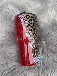 the red glitter tumbler with leopard print is sitting on a furry surface