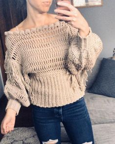 a woman taking a selfie with her cell phone while wearing ripped jeans and an off the shoulder sweater