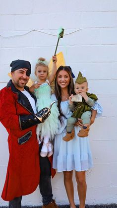 three people dressed up in costumes posing for a photo with one holding a doll and the other holding a doll