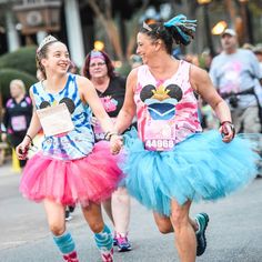 two women in costumes are running down the street with their hands in each other's pockets