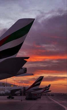 several airplanes are parked on the tarmac at an airport as the sun is setting