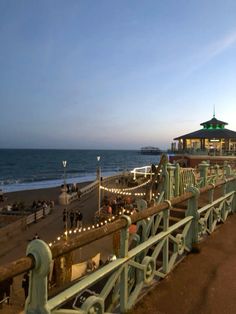 the boardwalk is lined with benches and lights along the water's edge at dusk