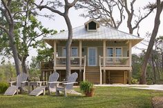 two lawn chairs sitting in front of a small wooden house with porches on the grass