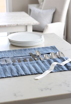 the table is set with utensils and silverware on blue denim napkins