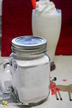 there is a mason jar with whipped cream in it next to a glass full of milkshake