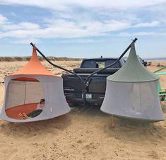 two tents set up on the beach next to a pickup truck with an awning