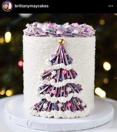 a white cake with purple icing and a christmas tree decoration on it's side