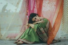 a woman sitting on the ground in front of sheer curtains