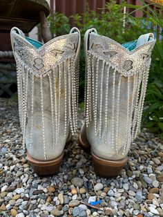 This stunning Corral Women's boot features delicate and flirty detailing, with chic white and silver colors. Its crystal fringe adds a touch of glamour, making it a versatile choice for any occasion. With its 8-inch shaft and silver trim, this over-the-ankle boot is sure to elevate your fashion game. You'll be impressed by the lightly crackled leather, giving it a unique look. VAMP LEATHER: Cowhide LINING: Pig TOE TYPE: Snip Toe SHAFT HEIGHT: 8" LOWER SHAFT WIDTH: 13" HEEL TYPE: Cowboy Heel HEEL Over The Ankle Boots, Ankle Cowgirl Boots, Crystal Fringe, Golden Mirror, Western Hats, Goodyear Welt, Black Mirror, Heel Type, Cowgirl Boots