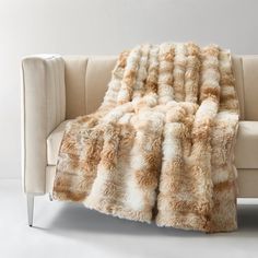 a couch with a blanket on it sitting in front of a white wall and floor