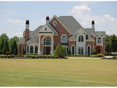 a large brick house with two chimneys in the front yard