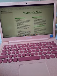 a pink laptop computer sitting on top of a bed