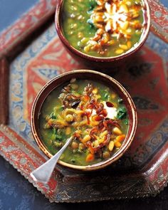 two bowls filled with soup sitting on top of a tray