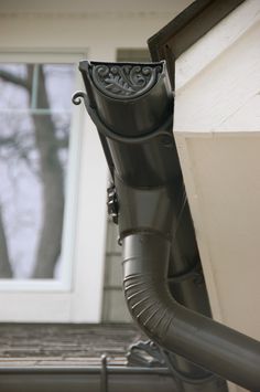 the pipe is attached to the side of the house and has an ornate design on it