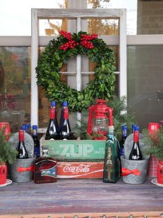 an assortment of liquor bottles and christmas wreaths on a window sill in front of a house