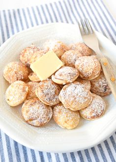 powdered sugar covered pastries on a plate with a butter knife and fork next to it