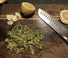 chopped up vegetables on a cutting board next to a knife and lemon wedges with one cut in half