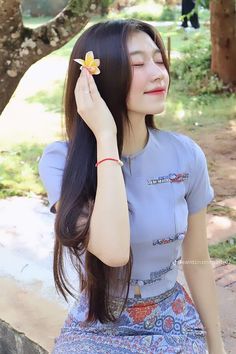 a woman with long hair holding a flower in her hand