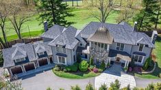 an aerial view of a large house with lots of trees in the front yard and driveway