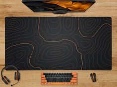 a computer mouse, keyboard and headphones sitting on a desk with a black surface