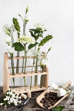 flowers in vases sitting on top of a wooden shelf next to chocolate bars and utensils