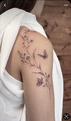 a woman's arm with flowers and butterflies on the left side of her shoulder