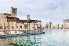 an empty dock in the middle of a body of water with buildings in the background