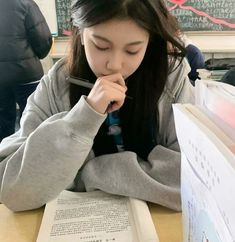 a woman sitting at a table with an open book in front of her and looking down