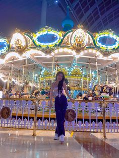 a woman standing in front of a carousel at night