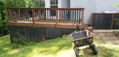 a wheelbarrow sitting in the grass next to a wooden deck with railings