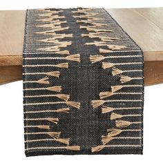 a table runner with tassels on it and a wooden table in the background