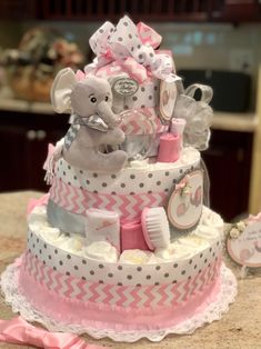 a diaper cake with an elephant and baby items on the top, sitting on a table