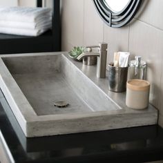 a bathroom sink sitting under a mirror next to a towel dispenser and toiletries