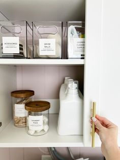 a person is holding the door handle on a cabinet full of containers and items that are labeled with labels